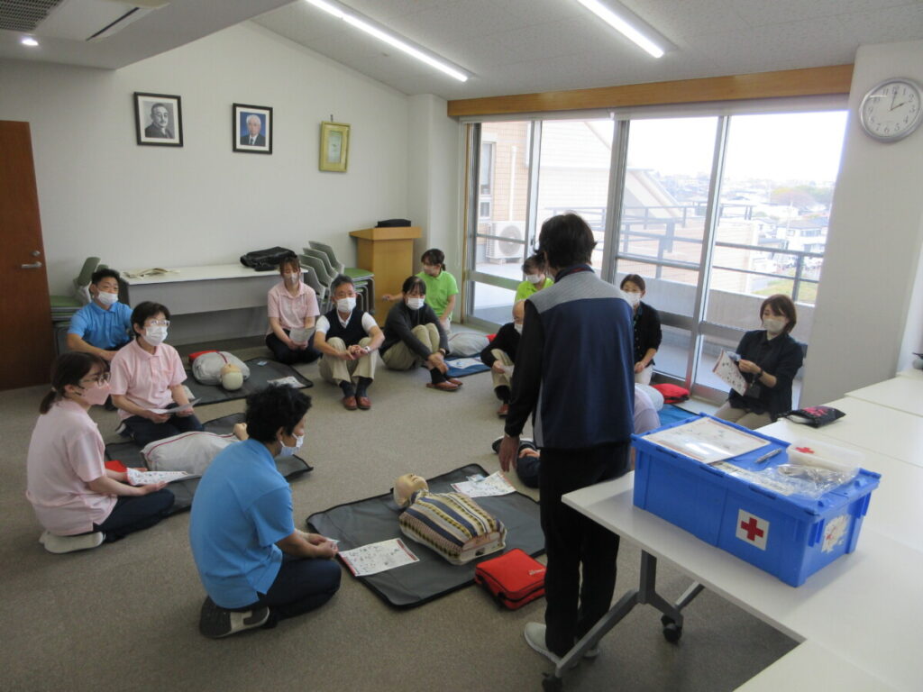 介護施設でのグループレクリエーション。入居者と職員が床座りで活動に参加している様子。