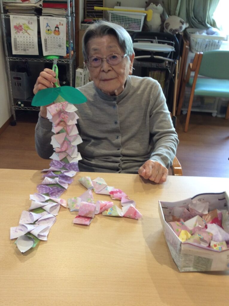 入居者が折り紙工作に取り組む様子。藤の花を製作中。